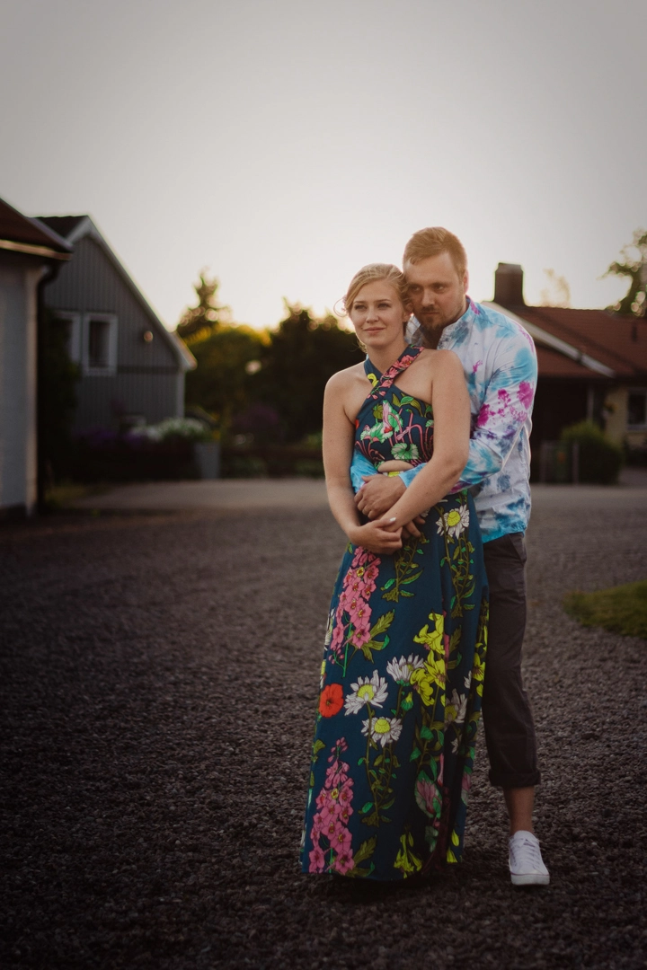 Groom has his arms wrapped around the bride in more 70's themed clothing during sunset